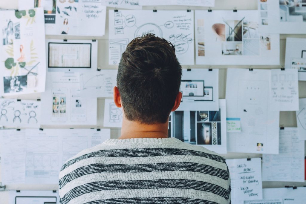 man looking at wall of calendars and papers representing planning